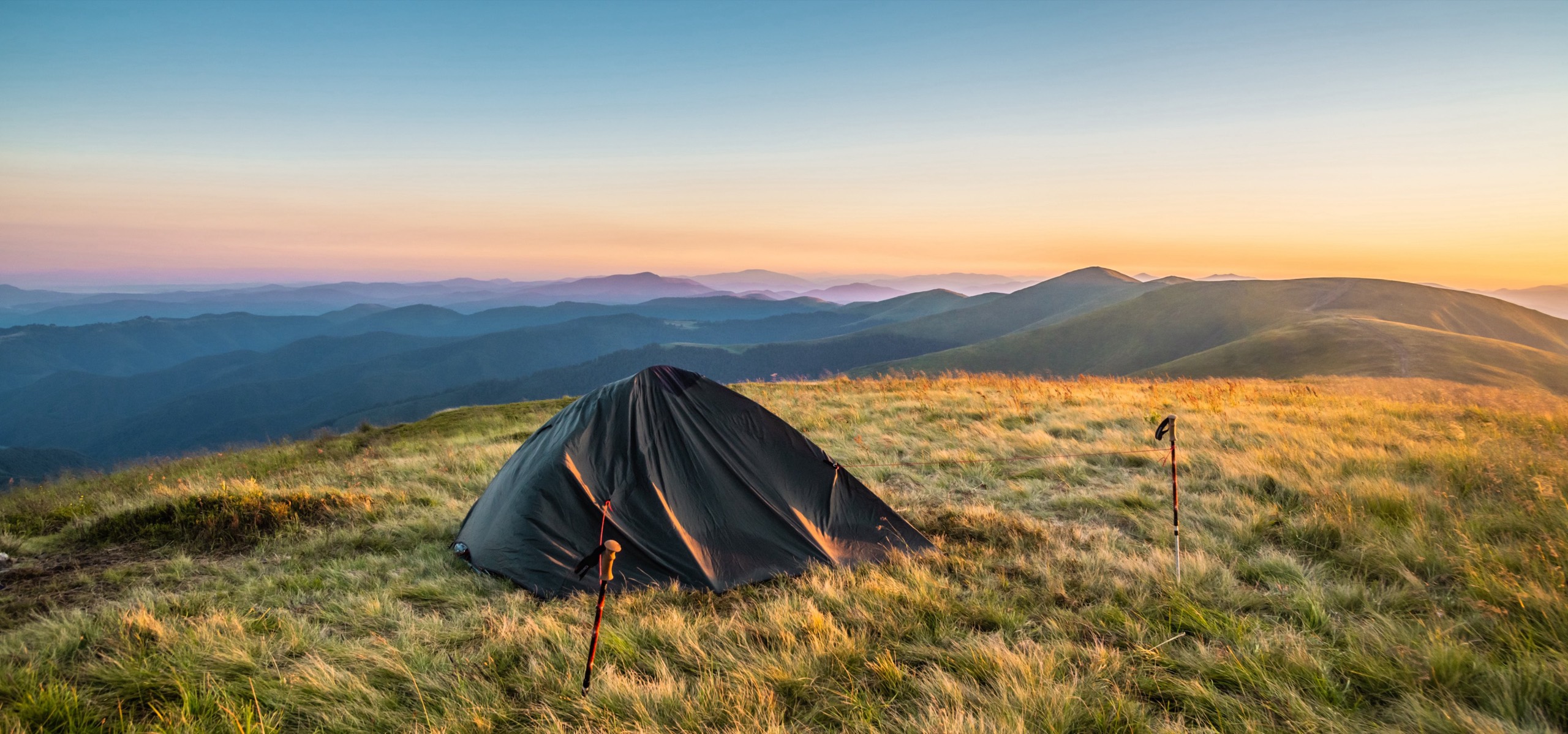 Zelt auf einem Bergkamm bei Sonnenaufgang über den Wolken